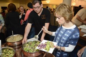 A woman is serving food to people at an event.