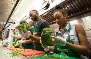 Two people holding broccoli in their hands