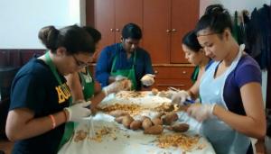 A group of people sitting around a table preparing food.