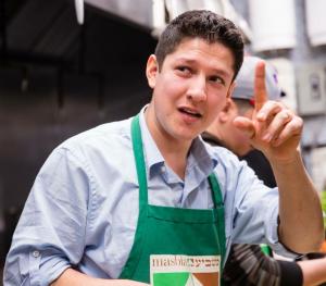 A man in an apron is holding his finger up.