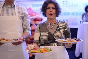 A woman holding a plate of food at a table.