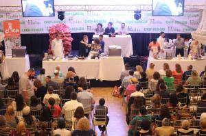 A crowd of people sitting around tables in front of microphones.