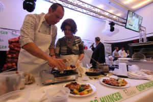 A man and woman preparing food on top of a table.