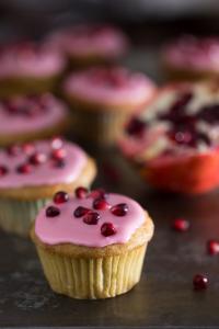 A close up of cupcakes with pink frosting and red sprinkles.