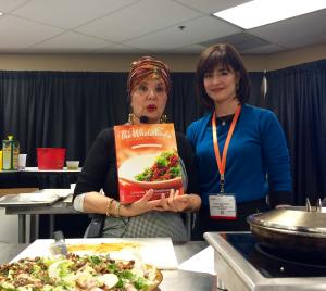 Two women standing in front of a table with food.