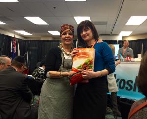Two women holding a bag of food in an office.