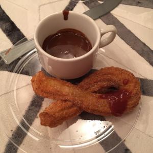 A cup of coffee and two pieces of food on a plate.