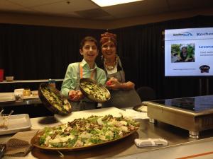 Two women holding plates of food in front of a screen.