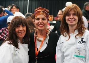 Three women standing next to each other in front of a crowd.