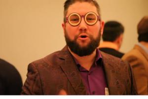 A man with glasses and beard in a suit.