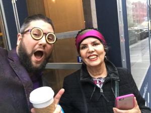A man and woman holding coffee cups in front of a window.
