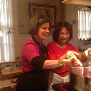 Two women smiling while stirring pot in kitchen