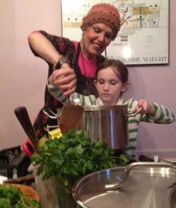 Woman and girl stirring large pot together