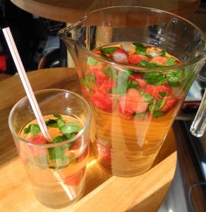 A wooden table with two glasses and a pitcher of fruit.
