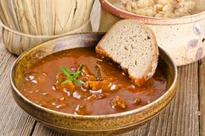A bowl of soup with bread on the side.