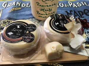 A couple of cheese on top of a wooden board.