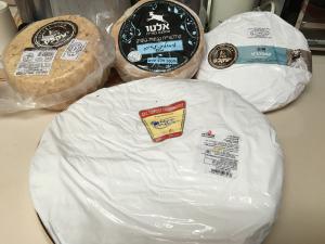 A close up of several cheeses on display.