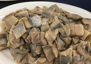 Pickled herring pieces on white plate