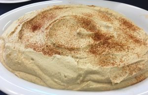A white plate topped with hummus covered in cinnamon.