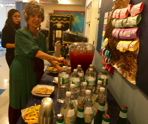 A woman standing at the table with many bottles of juice.
