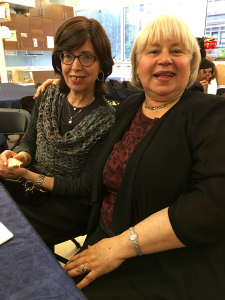 Two women sitting at a table with food.