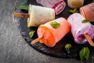 Colorful creamy fruit popsicles garnished with mint