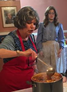 A woman in an apron is lighting candles.