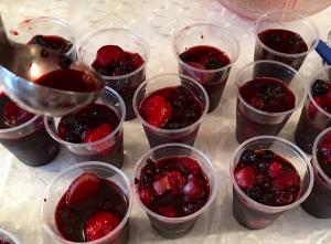 A table with many cups of fruit on it