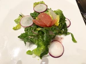 A salad with lettuce, radishes and grapefruit.