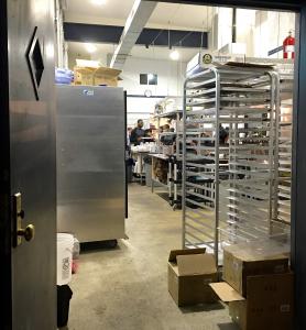 A kitchen with many trays of food in it.