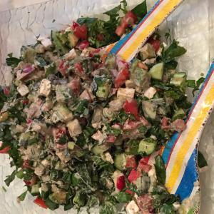 A large salad with two forks and some meat