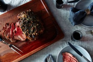 A wooden tray with meat and wine on it.