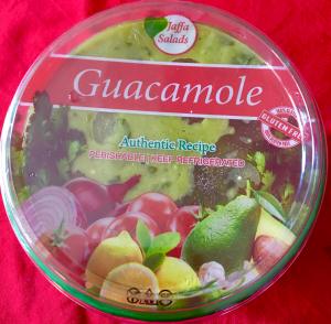 A round container of guacamole on top of a red cloth.