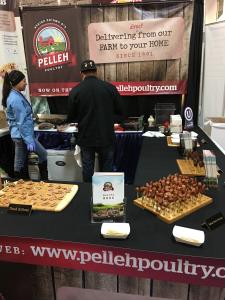 A couple of people standing around some pizza.