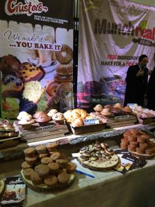 A table full of food and people standing around.