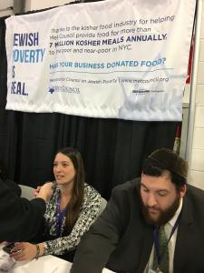 Two people sitting at a table under a sign.