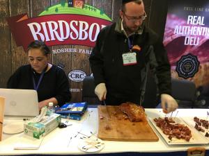 Deli vendor slicing smoked meat at trade booth