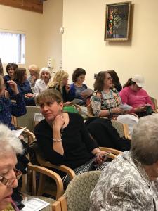 A group of people sitting in chairs and some are looking at something.