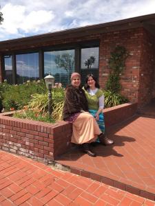 Two women sitting on a bench outside of a building.