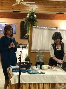 Two women standing at a table with food.