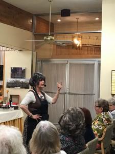 A woman in an apron is talking to people.