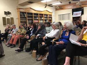 A group of people sitting in front of a book case.