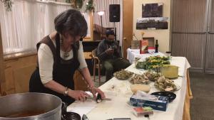 A woman cutting paper at a table with plants.