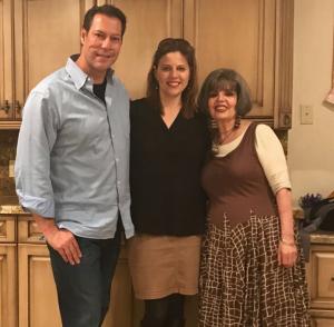 A man and two women standing in front of a kitchen.