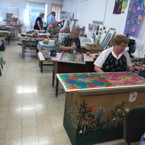 A group of people sitting at tables in an art studio.