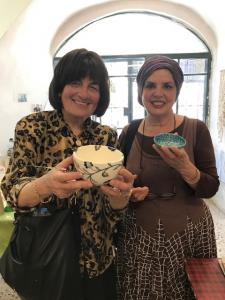 Two women smiling holding handmade ceramic bowls
