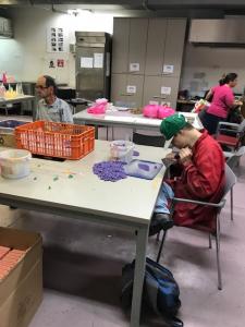 Workshop scene: people assembling colorful craft pieces