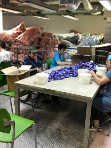 People assembling packaged snacks at warehouse table