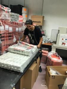 A man in black shirt and hat working on boxes.
