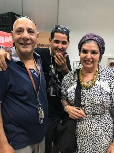 Three smiling people, woman wearing headscarf